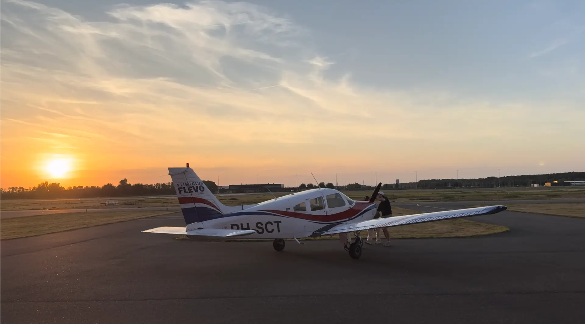 De Piper PA-28 Warrior II PH-SCT bij zonsondergang op het platform van Lelystad Airport