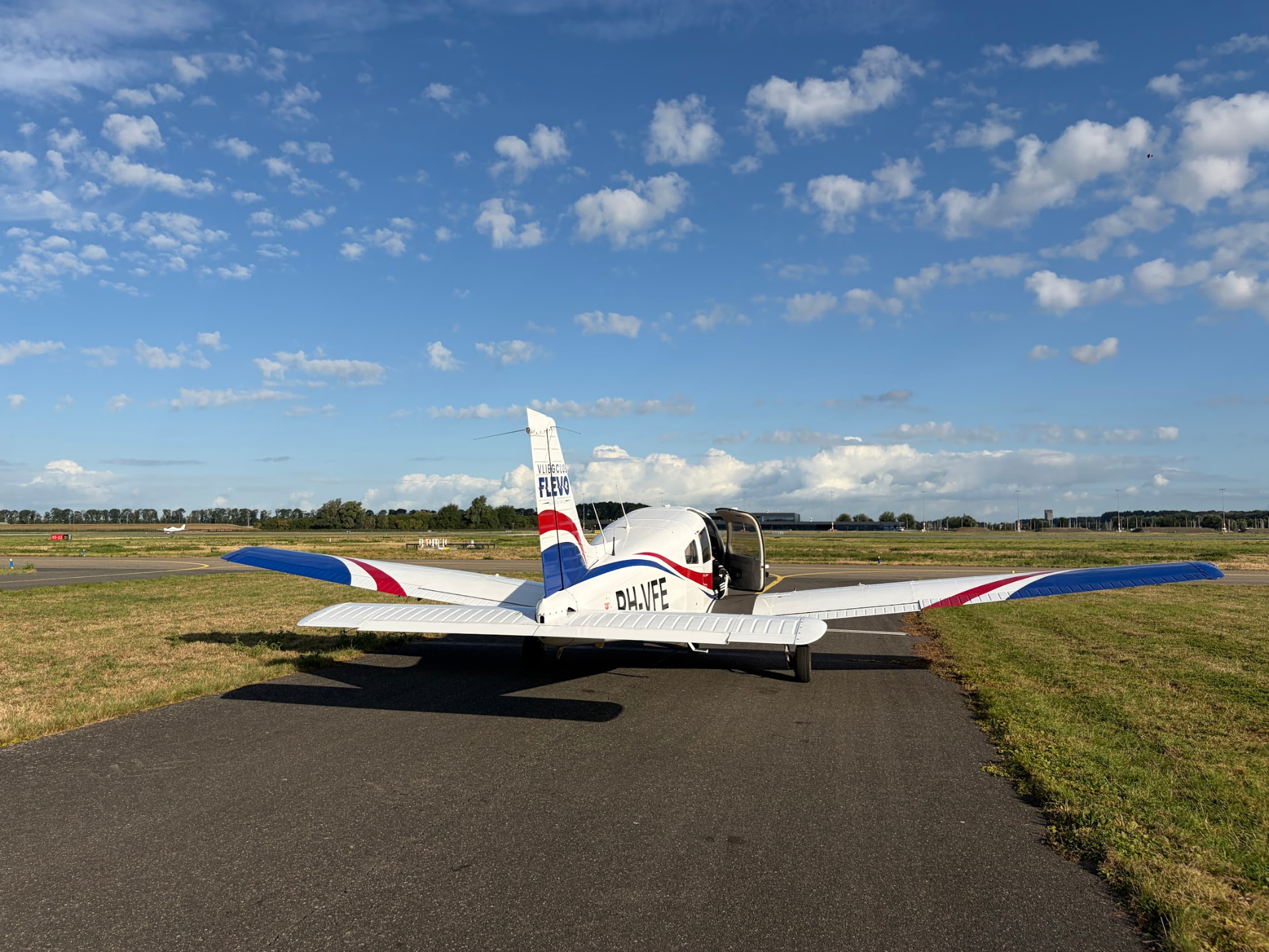 De Piper PA-28 Warrior III PH-VFE met open cabinedeur op de taxibaan van Lelystad Airport