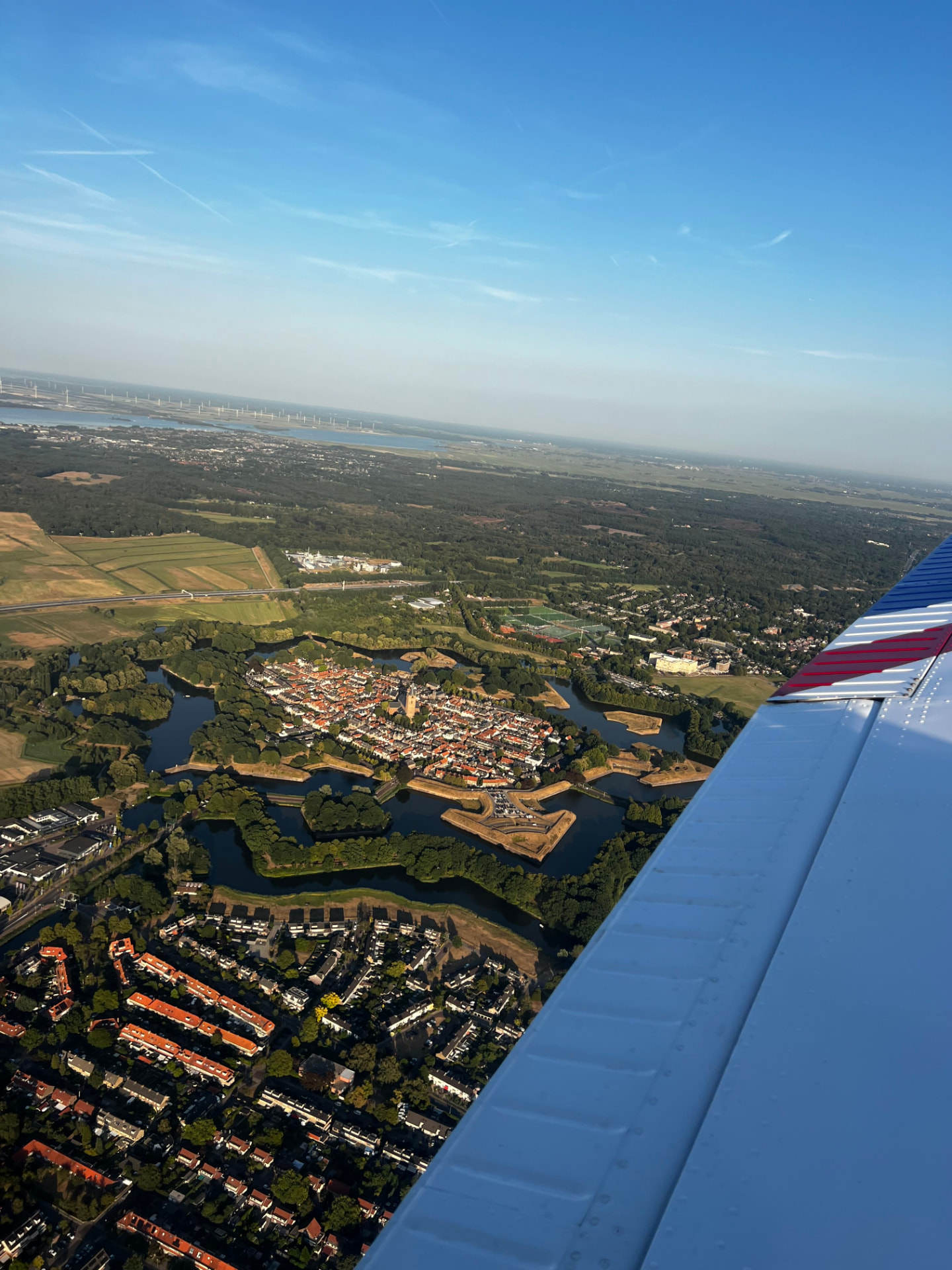 De stervormige vestingstad Naarden vanuit de lucht, met de vleugel van de Piper in beeld