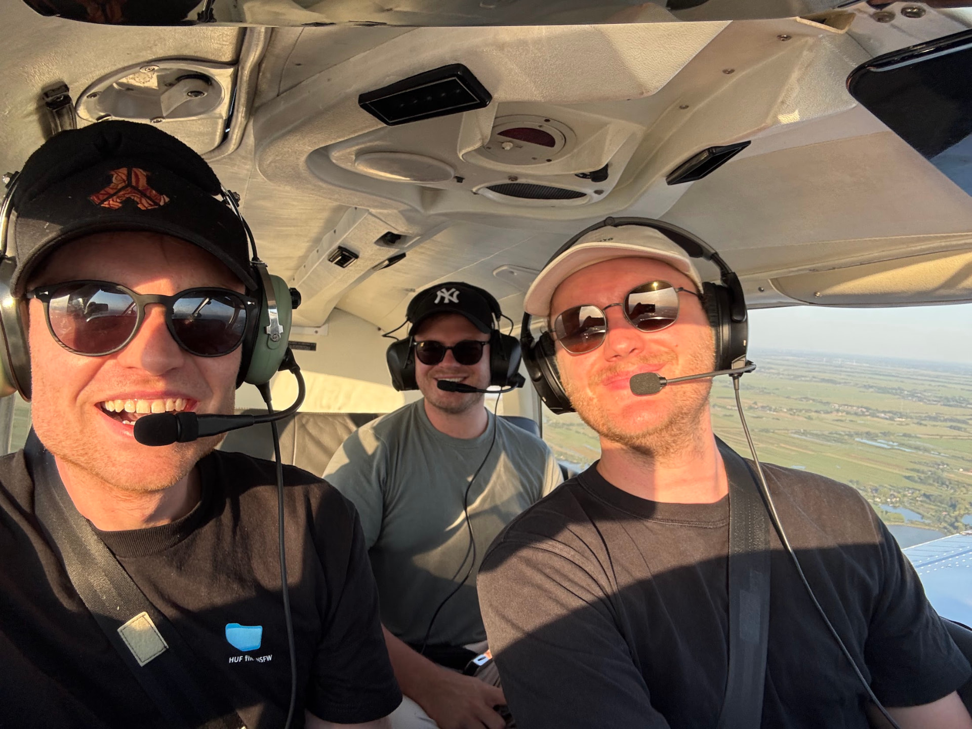 Drie lachende inzittenden met headsets in de cockpit tijdens een rondvlucht boven de polders