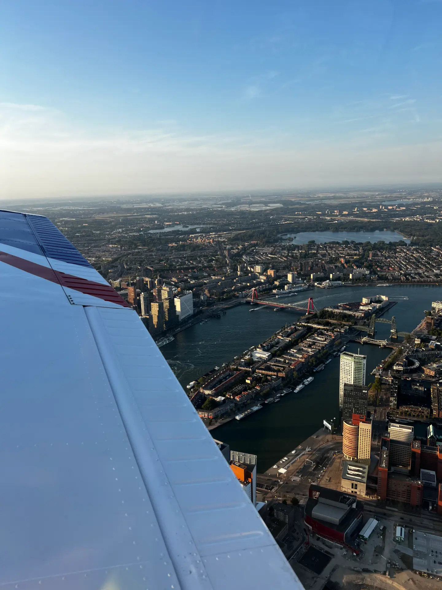 De Willemsbrug en de Maas met de Kop van Zuid, gezien over de vleugel van de Piper
