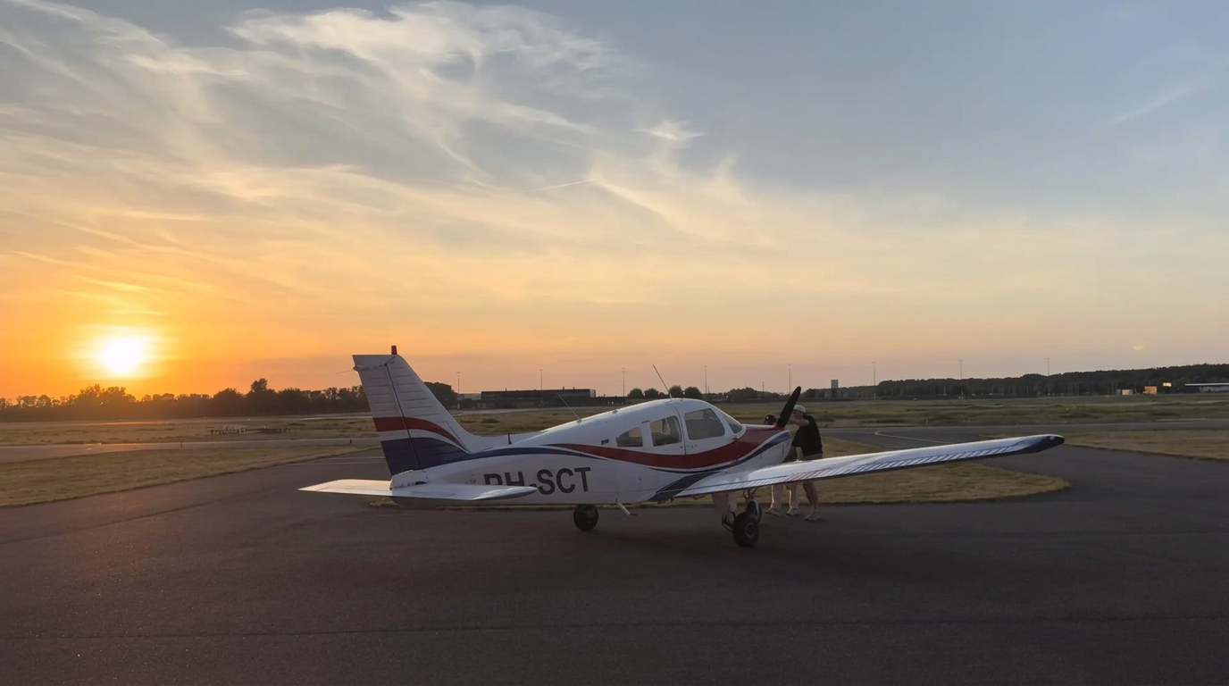 Piper PA-28 Warrior II PH-SCT bij zonsondergang op het platform van Lelystad Airport klaar voor een rondvlucht boven Nederland