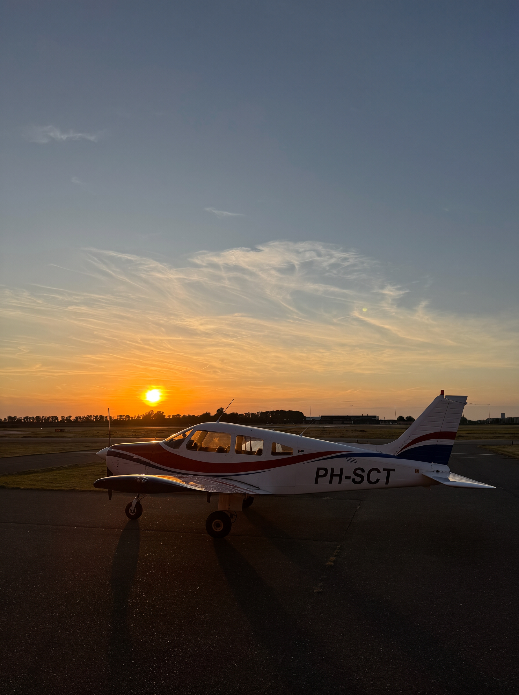 De Piper PA-28 Warrior PH-SCT op het platform van Lelystad Airport bij zonsondergang klaar voor een rondvlucht