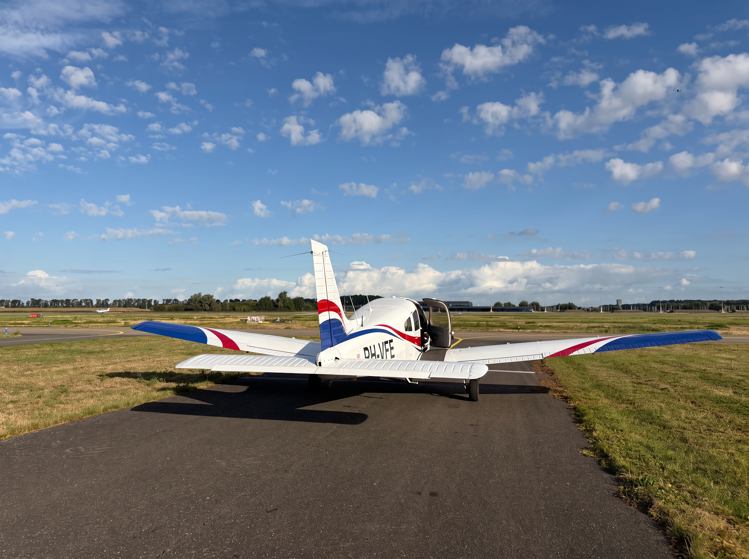 Piper PA-28 Warrior III PH-VFE met open cabinedeur op de taxibaan van Lelystad Airport voor een rondvlucht Amsterdam of Texel